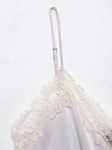 Detail of silk satin camisole featuring white floral lace trim and adjustable strap