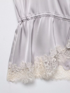 Detail of silver satin top featuring a drawstring waist and delicate eyelash lace hem