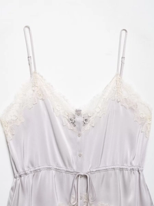 Close-up of silver satin top with delicate white eyelash lace and button detail