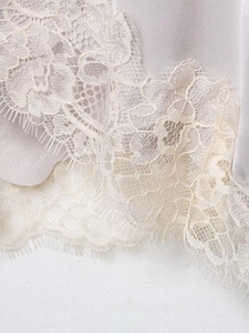 Detailed close-up of lavender satin fabric with delicate eyelash lace trim on top