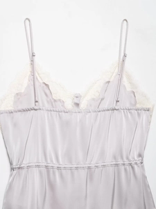Detail of silver satin camisole featuring white lace trim and adjustable thin straps