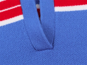Détail du col en V d'un pull en maille à rayures de couleur rouge, blanche et bleue