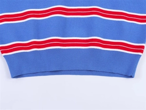 Détail du pull en maille bleue à rayures rouges et blanches avec un ourlet côtelé