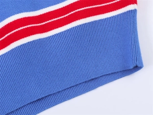 Détail de la manche d'un pull en maille bleu roi avec bord-côte à rayures rouges et blanches