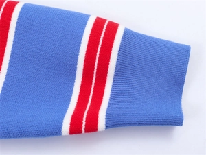 Détail d'une manche en tricot bleu avec rayures rouges et poignets côtelés sur le pull
