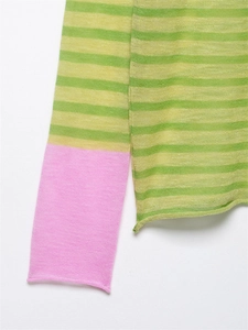 Détail d'un pull en maille rayée verte avec poignets roses et texture de tissu doux