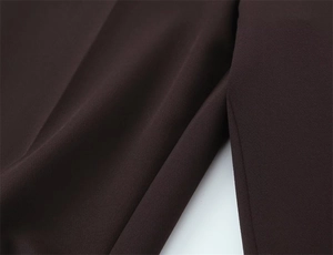 Gros plan du pantalon évasé fendu montrant le tissu marron texturé et les coutures