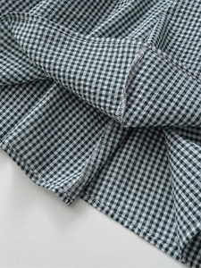 Dettaglio della cucitura overlock e dell'orlo sul vestito midi a quadretti verdi e bianchi