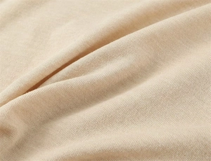 Vue macro du tissu en maille fine abricot montrant une texture douce et un tissage fin