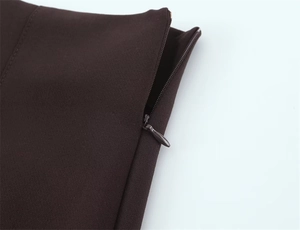 Détail d'une fermeture éclair invisible en métal sur un pantalon évasé marron foncé