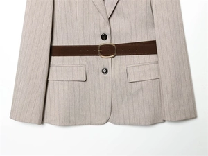 Detail eines hellgrauen Blazers mit Fischgrätmuster und dunkelbraunem Gürtel
