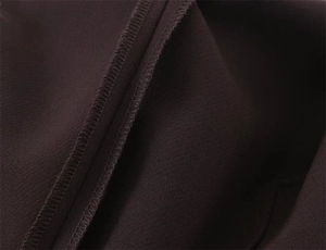 Vue détaillée de la couture surjet de qualité sur le tissu de pantalon marron