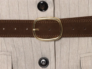 Detail eines Fischgräten-Blazers mit dunkelbraunem Wildleder-Gürtel und goldener Schnalle