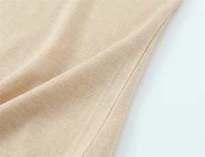 Détail du tissu en maille beige montrant la texture fine et les coutures de qualité