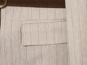 Detailaufnahme von Fischgräten-Stoff mit dunkelbraunem Gürtel und goldener Schnalle