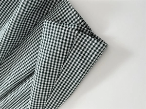 Dettaglio del tessuto vichy verde e bianco con cuciture rifinite e drappeggio fine