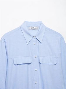 Dettaglio camicia a righe azzurre con tasche simmetriche ed etichetta sul retro