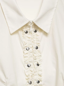 Détail d'une chemise en popeline avec volants superposés, clous argentés et zip frontal