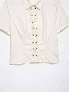 Détail du col à volants plissés et des rivets argentés sur cette chemise en popeline