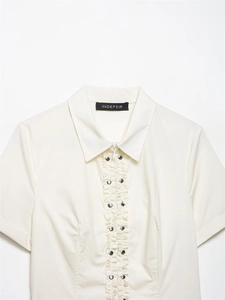 Détail de volants à l'avant avec boutons-pression argentés sur chemise en popeline crème