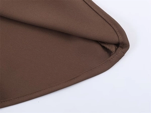Macro shot of the dark brown asymmetrical hem featuring precision stitched rolled edges