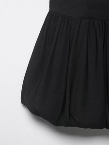 Detailed view of the black bubble hem with intricate pleats and matte woven fabric