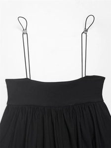 Close-up of black top adjustable thin straps with silver buckles and pleated neckline