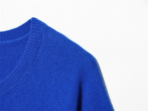 Détail du col rond côtelé sur un pull en maille bleu marine avec texture en jersey