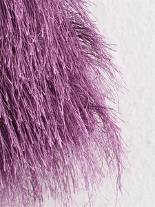 Detalle de tela con flecos morados que muestra textura de fibra y caída elegante