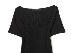 Detail of black off-shoulder top featuring intricate smocked texture and elastic shirring