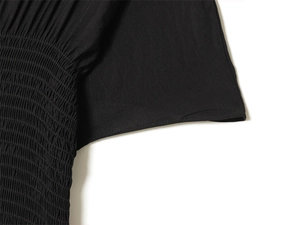 Close-up of smocking detail on black slim fit dress with precise stitching and fabric texture