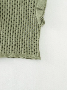 Detail van grasgroene gebreide top met mesh-patroon en mouwen met ruches