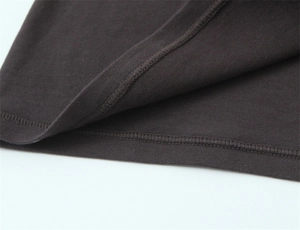 Macro shot of double-needle stitching on dark knit top hem with dense fabric texture