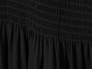 Detail view of refined smocking texture and elastic pleated fabric on black dress