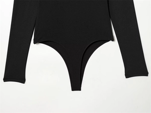 Detail view of a slim-fit black long-sleeve bodysuit with a high-quality knit texture
