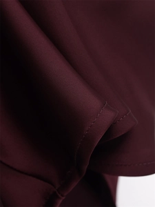 Detailed close-up of dark burgundy satin fabric with refined stitching and smooth texture