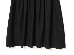 Close-up of black pleated fabric dress featuring fine texture and stitched hem detail