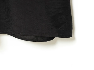 Close-up of black dress hem showing precision stitching and textured crepe fabric