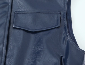 Dettaglio ravvicinato della tasca del gilet in pelle blu scuro con cuciture e trama