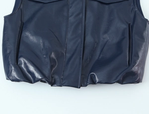 Dettaglio dell'orlo del gilet effetto pelle blu scuro con elastico e tasche laterali