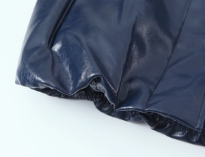 Dettaglio dell'orlo elastico e delle cuciture sulla giacca in ecopelle blu scuro lucida