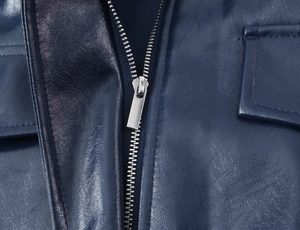 Dettaglio del gilet in ecopelle blu scuro con cerniera metallica e cuciture delle tasche