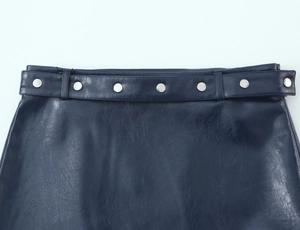 Dettaglio della gonna in ecopelle blu scuro con cintura coordinata e bottoni in metallo argento