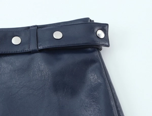 Dettaglio gonna in ecopelle blu scuro con borchie in metallo argento e cucitura cintura