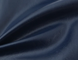 Primo piano del tessuto in pelle blu scuro con trama fine e riflessi lucidi delicati