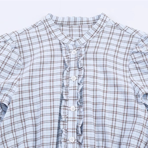 Blauwe geruite blouse met opstaande kraag, ruches en witte knopen in detailweergave
