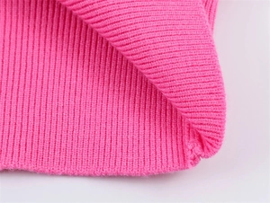 Gros plan sur la maille côtelée rose vif montrant les coutures et la texture du tissu