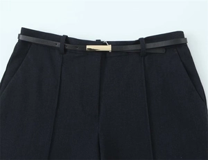 Dettaglio dei pantaloni dritti a vita alta con pieghe e cintura sottile dorata