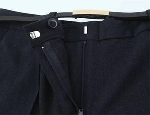 Dettagli dei pantaloni blu scuro con gancio metallico, bottone e cintura sottile con fibbia