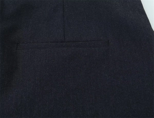 Dettaglio di una tasca a filetto su pantaloni dritti scuri con sartoria di alta qualità